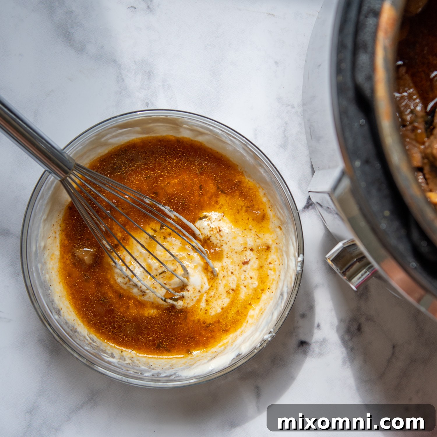 the hot broth being whisked into the sour cream mixture.