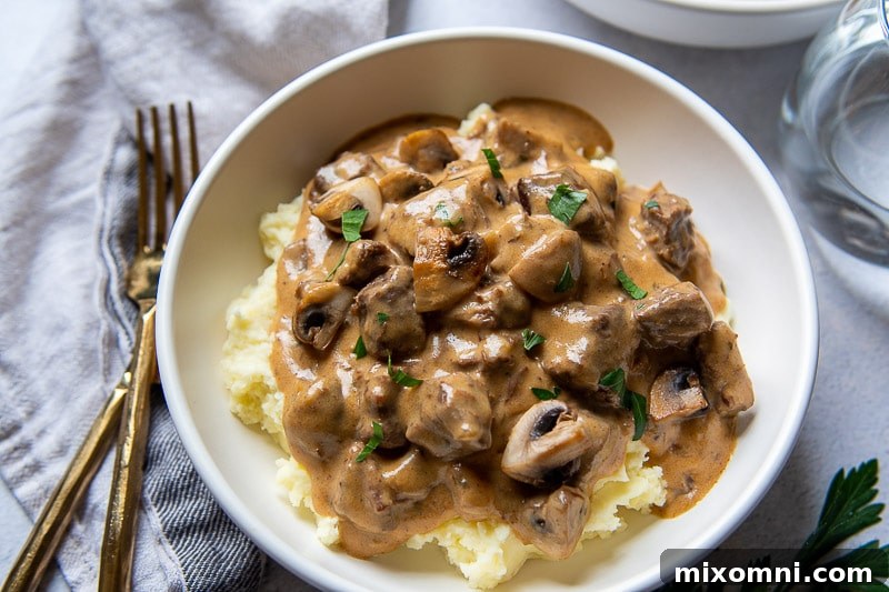 overhead shot of a dinner setting with a bowl of stroganoff and gold forks and knives next to it
