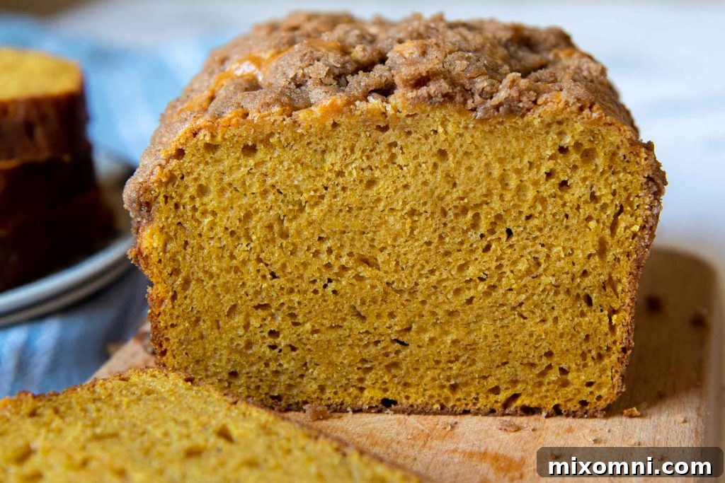 A freshly baked gluten-free pumpkin bread loaf, beautifully sliced open to reveal its moist and tender crumb.