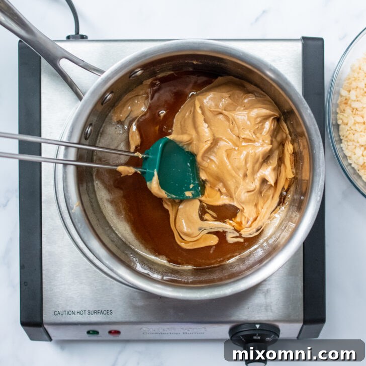 The peanut butter and sugar mixture being combined in a saucepan on the stovetop, creating the base for the cookies.