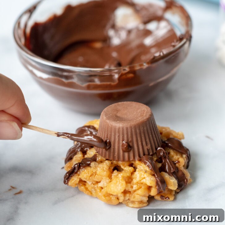 A toothpick applying small chocolate dots to a peanut butter cup, preparing to adhere the candy eyeballs.