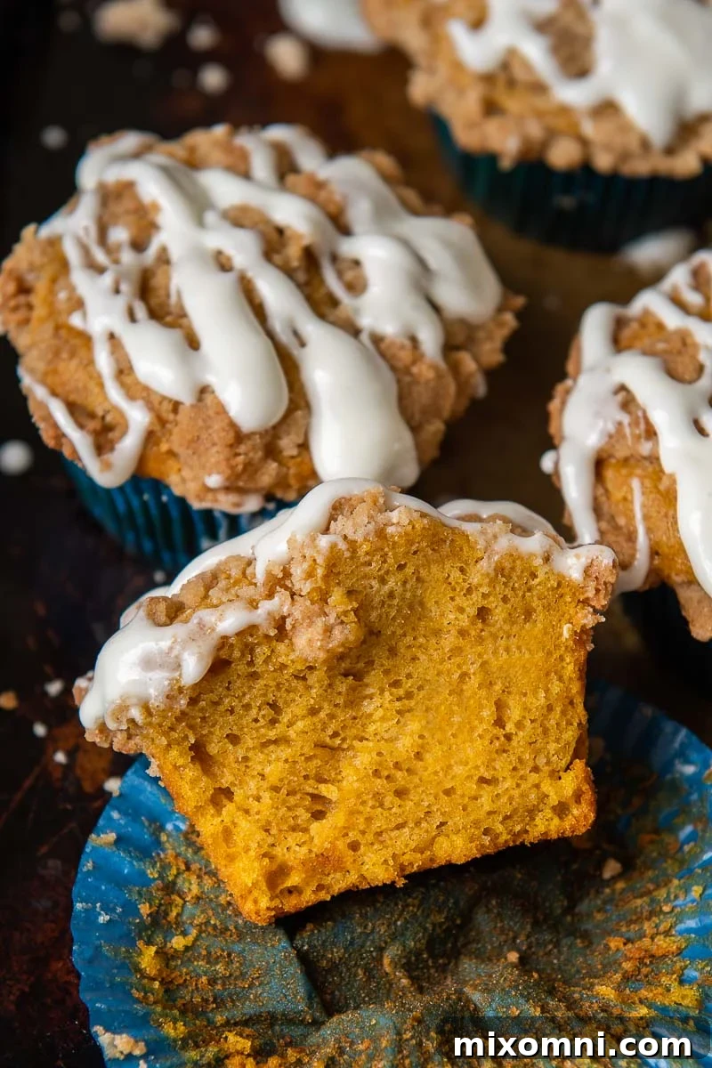 a pumpkin muffin split open and resting on a muffin liner