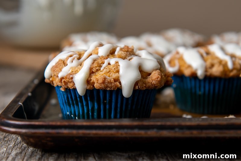a straight on view of gluten free pumpkin muffin with crumb topping and glaze on top