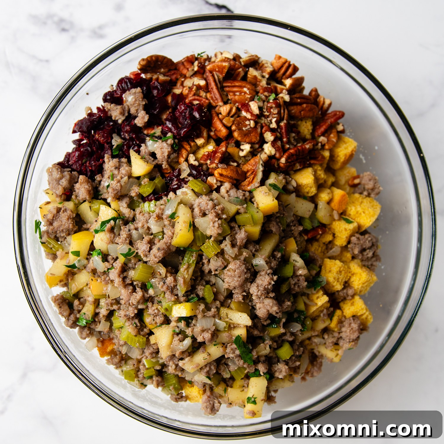 All the gluten-free cornbread stuffing ingredients, including dried cornbread, sausage mixture, cranberries, and pecans, combined in a large bowl, ready for baking.