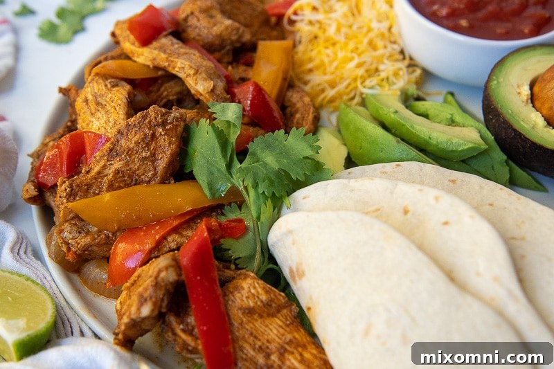 Close-up of vibrant chicken fajita meat served on a plate with fresh toppings like cilantro and lime wedges.