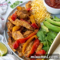 plate of chicken fajita meat, peppers, onions with a bowl of salsa