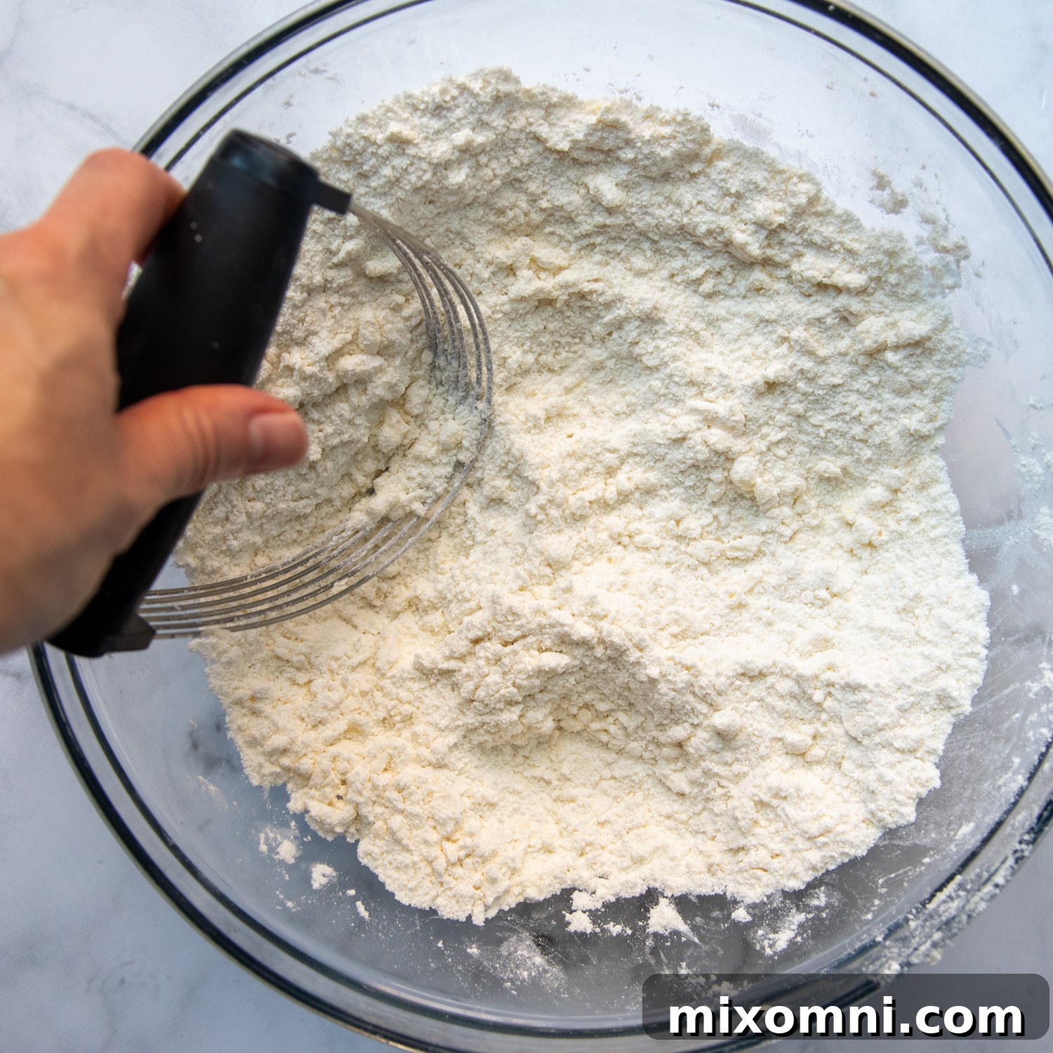 Cold butter being cut into gluten-free flour mixture with a pastry blender.