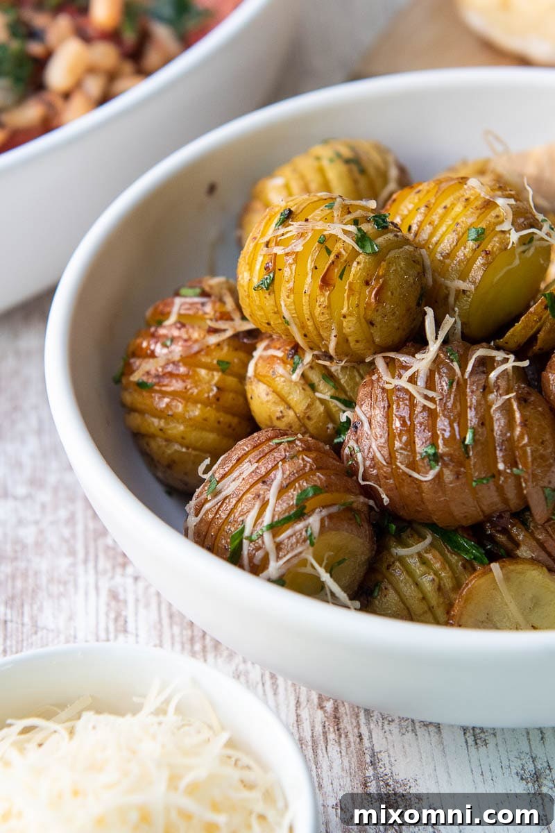 Red potatoes in a white bowl with melted Parmesan cheese and fresh parsley garnish.