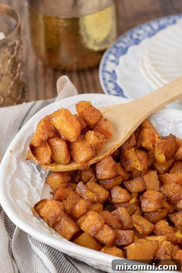 a wooden spoon lifting out a serving of roasted butternut squash