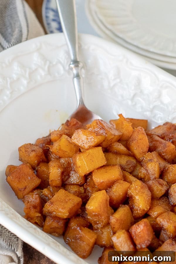 a spoon resting in a serving bowl with roasted butternut squash