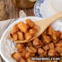 a wooden spoon lifting out a serving of roasted butternut squash