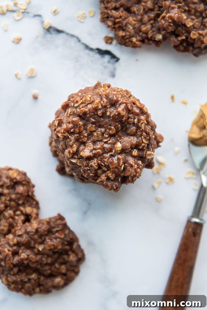 An overhead shot of a stack of Preacher Cookies, with a spoon of creamy peanut butter resting beside them.