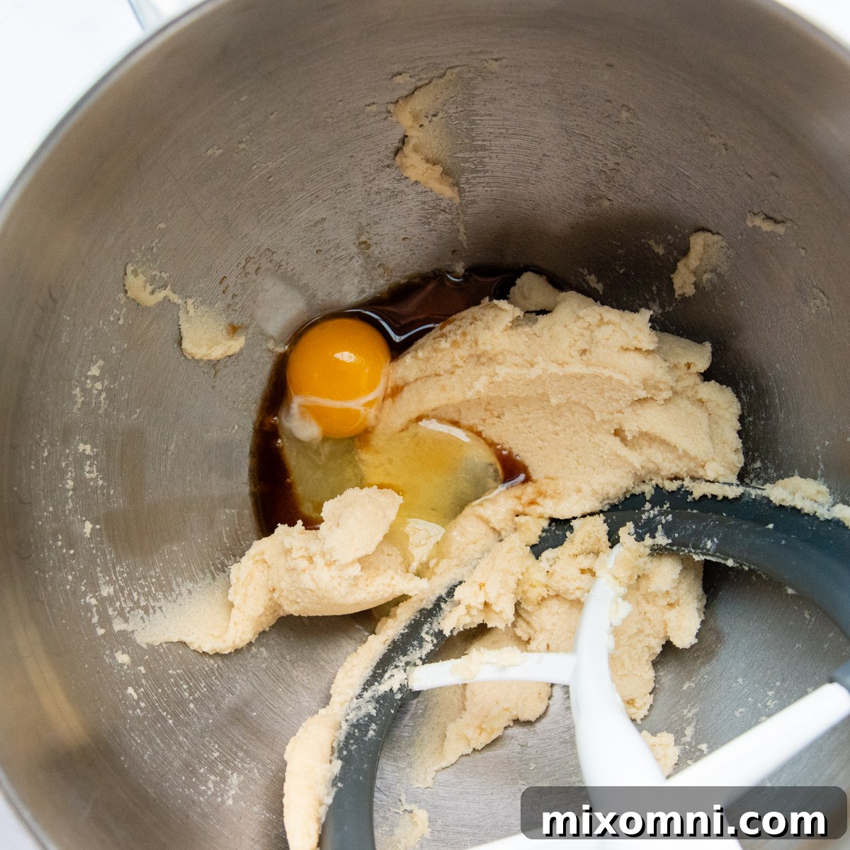 Creamy mixture of softened butter and sugars in a mixing bowl.