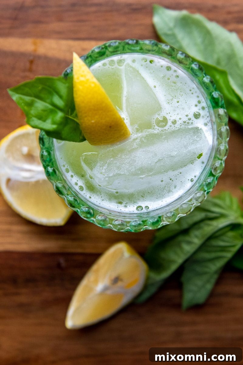 A top-down view of a perfectly crafted gin basil smash cocktail, surrounded by fresh lemons and basil leaves, highlighting its refreshing and vibrant appearance.