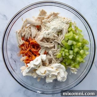 All the vibrant ingredients for the buffalo chicken topping, including shredded chicken, celery, hot sauce, and cream cheese, prepped and ready for mixing.