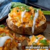 A buffalo chicken baked potato with ranch dressing drizzled over top, indicating a delicious and comforting meal.