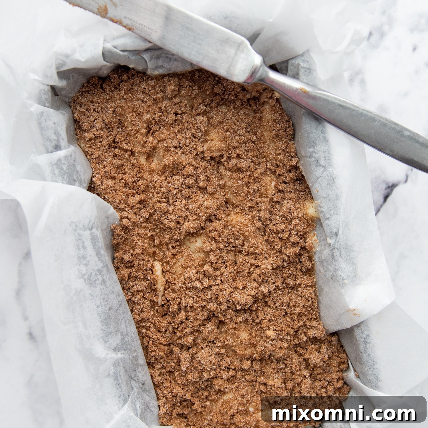 Gluten-free cinnamon bread with streusel topping in the loaf pan, ready for baking.