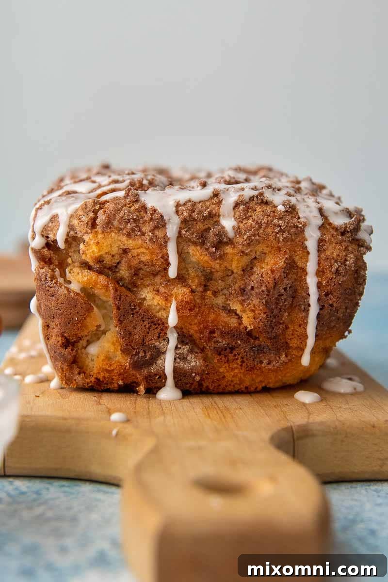 A whole loaf of uncut gluten-free cinnamon bread with vanilla glaze dripping down the sides.