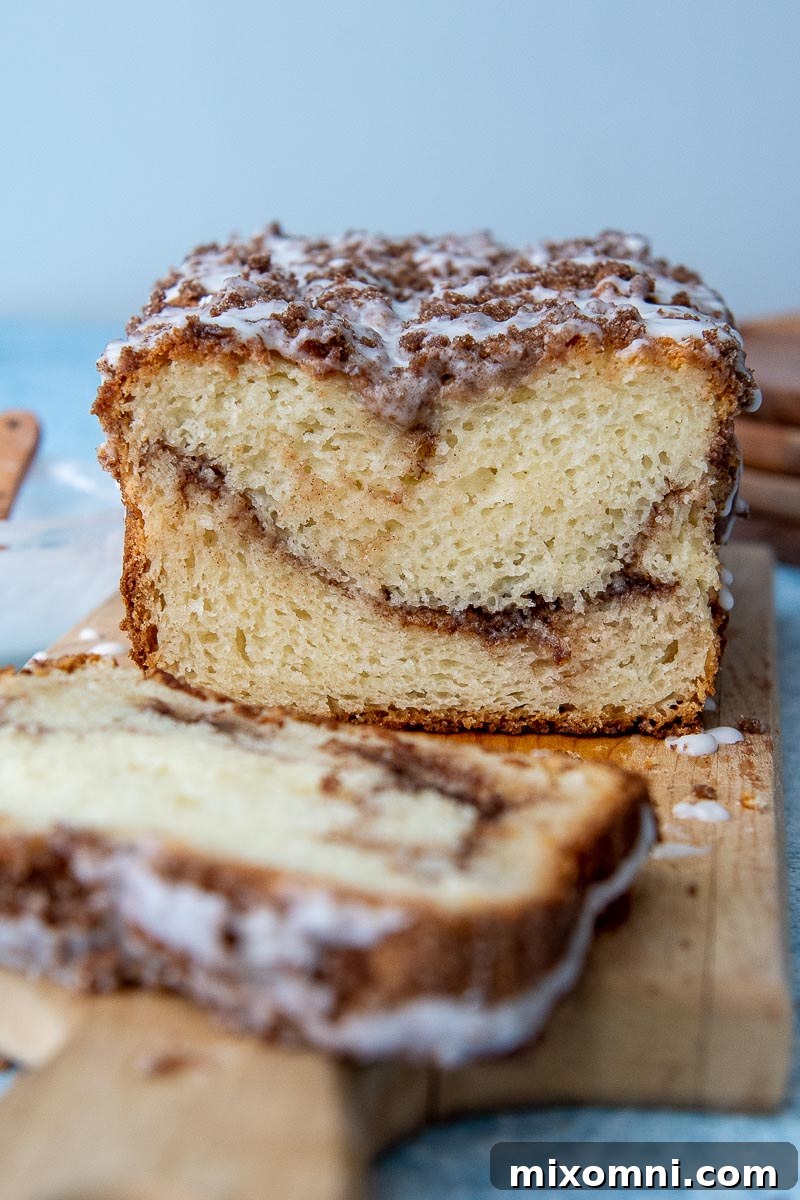 Slices of gluten-free cinnamon bread arranged on a wooden cutting board with a whole loaf in the background.