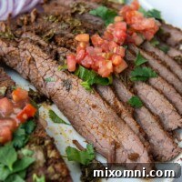 sliced flank steak on a plate with pico over top