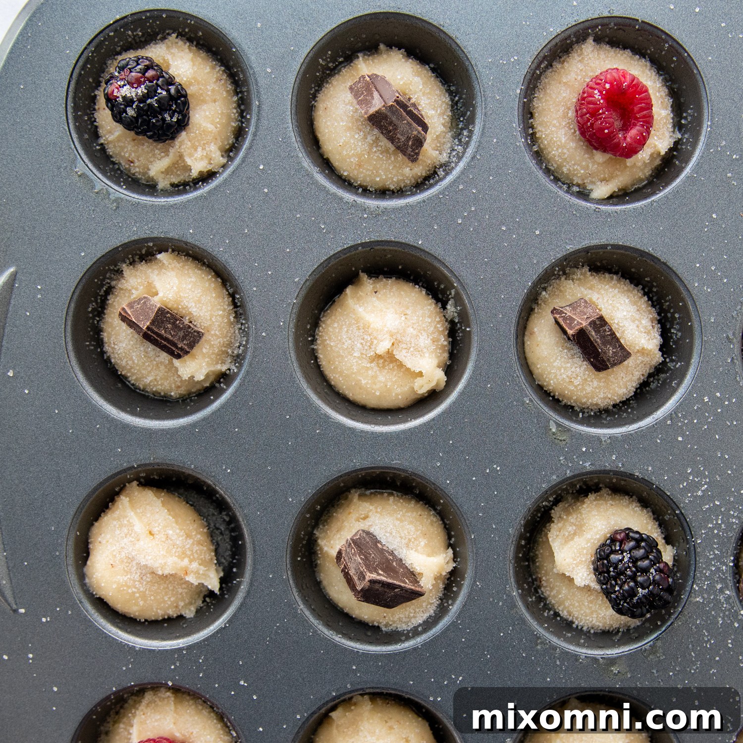 overhead shot of all the mini tea cakes with chocolates and berries on top before baking.