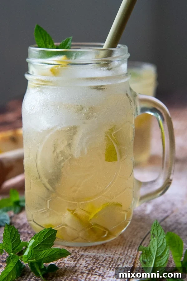 A refreshing ginger cocktail adorned with fresh mint and a pear slice, ready to be enjoyed.