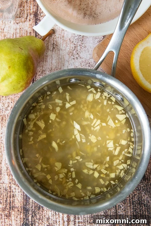 A saucepan filled with fresh chopped ginger simmering in simple syrup, essential for any ginger cocktail.