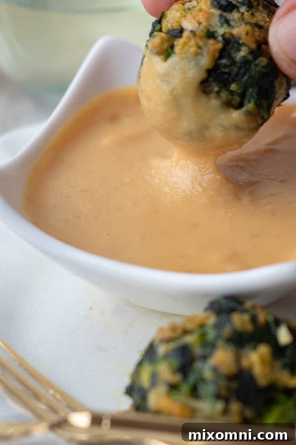 A crispy spinach ball being dipped into the rich, spicy sweet mustard sauce, highlighting the perfect pairing.