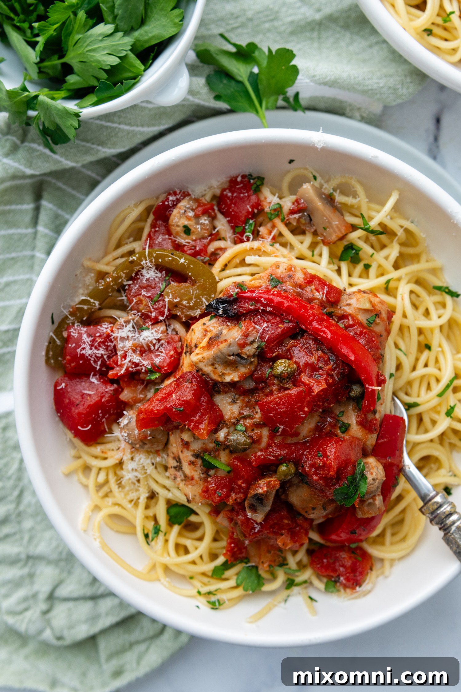 overhead shot of chicken cacciatore served over pasta, showcasing tender chicken, colorful vegetables, and rich tomato sauce.