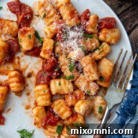 overhead shot of gnocchi on a white plate with a fork resting on it