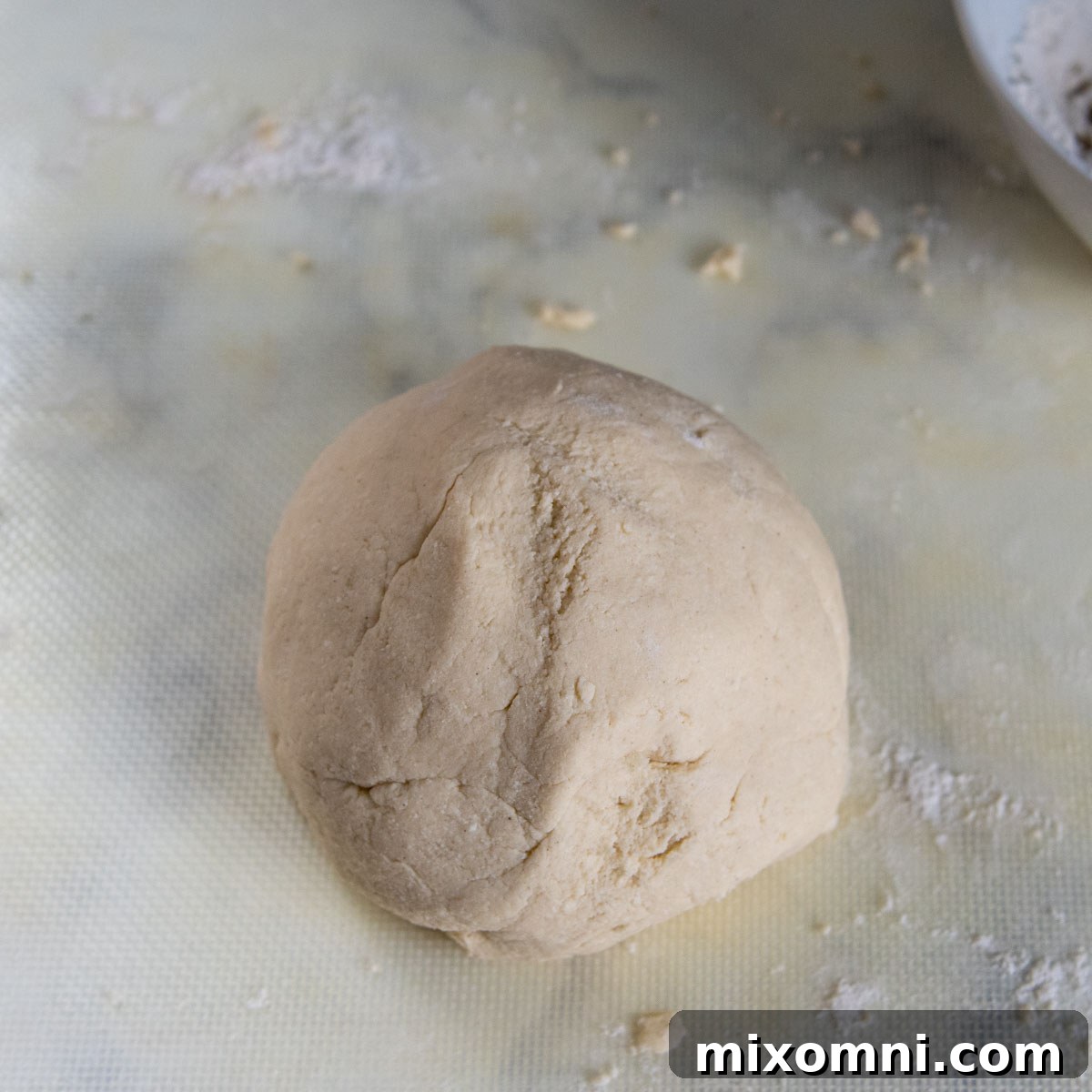 Gluten-free gnocchi dough, freshly kneaded into a smooth, round ball, resting on a lightly floured surface, ready for shaping.