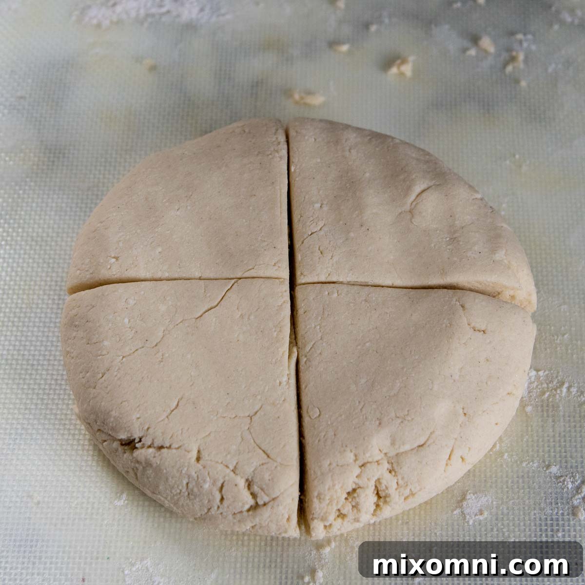 Gluten-free gnocchi dough flattened into a thick disc and carefully cut into four equal sections, preparing for rolling.