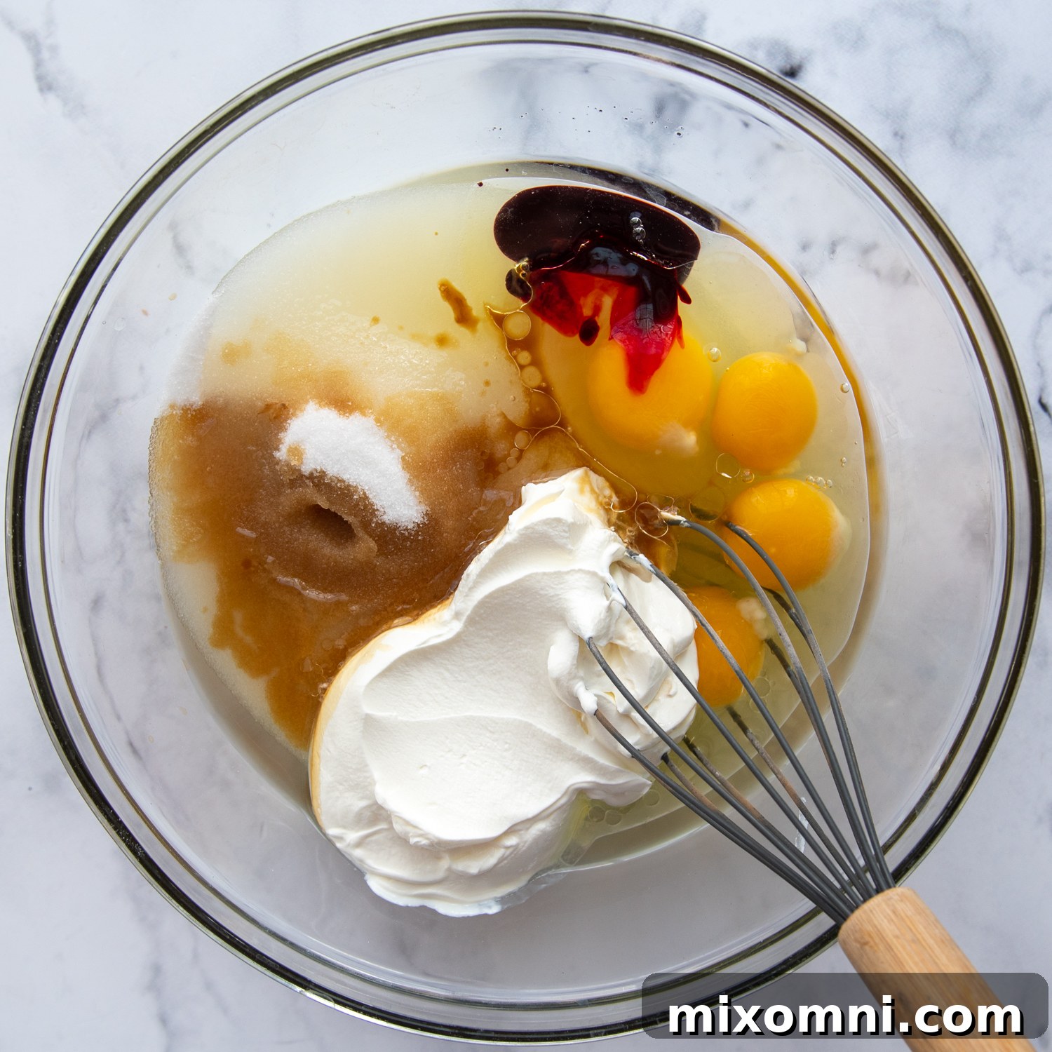 glass bowl with liquid ingredients being whisked together.
