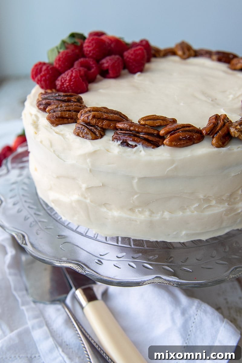 close up of cream cheese frosting and candied pecans on the layer cake
