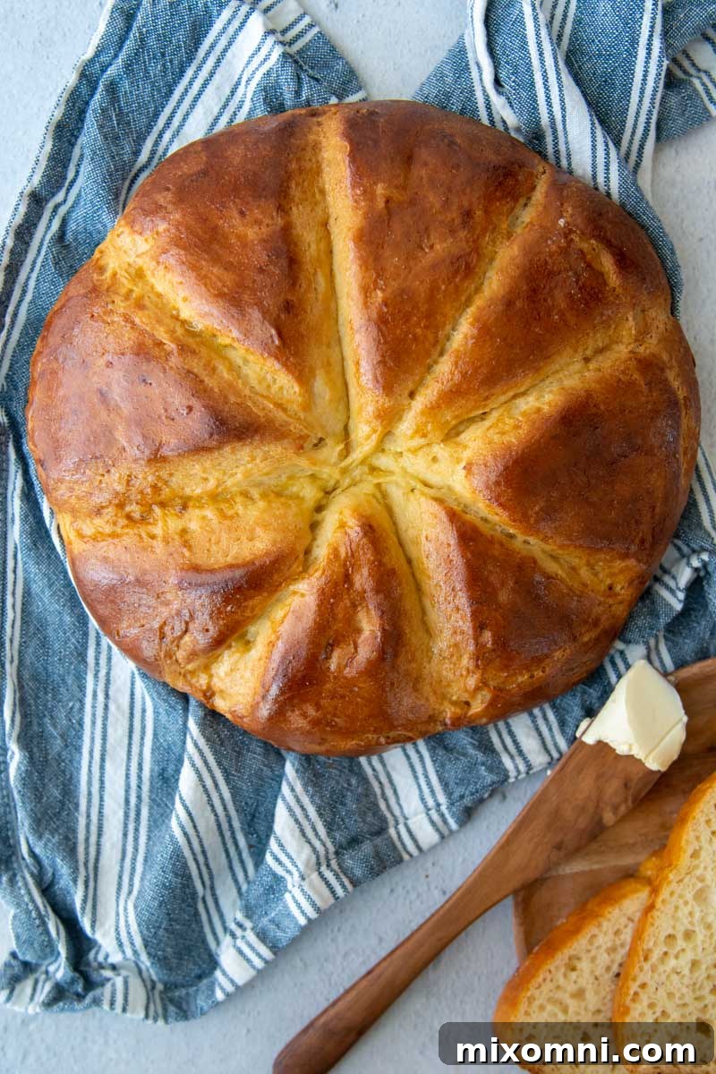 The top crust of a beautifully baked gluten-free challah loaf resting on a blue towel, ready to be enjoyed.