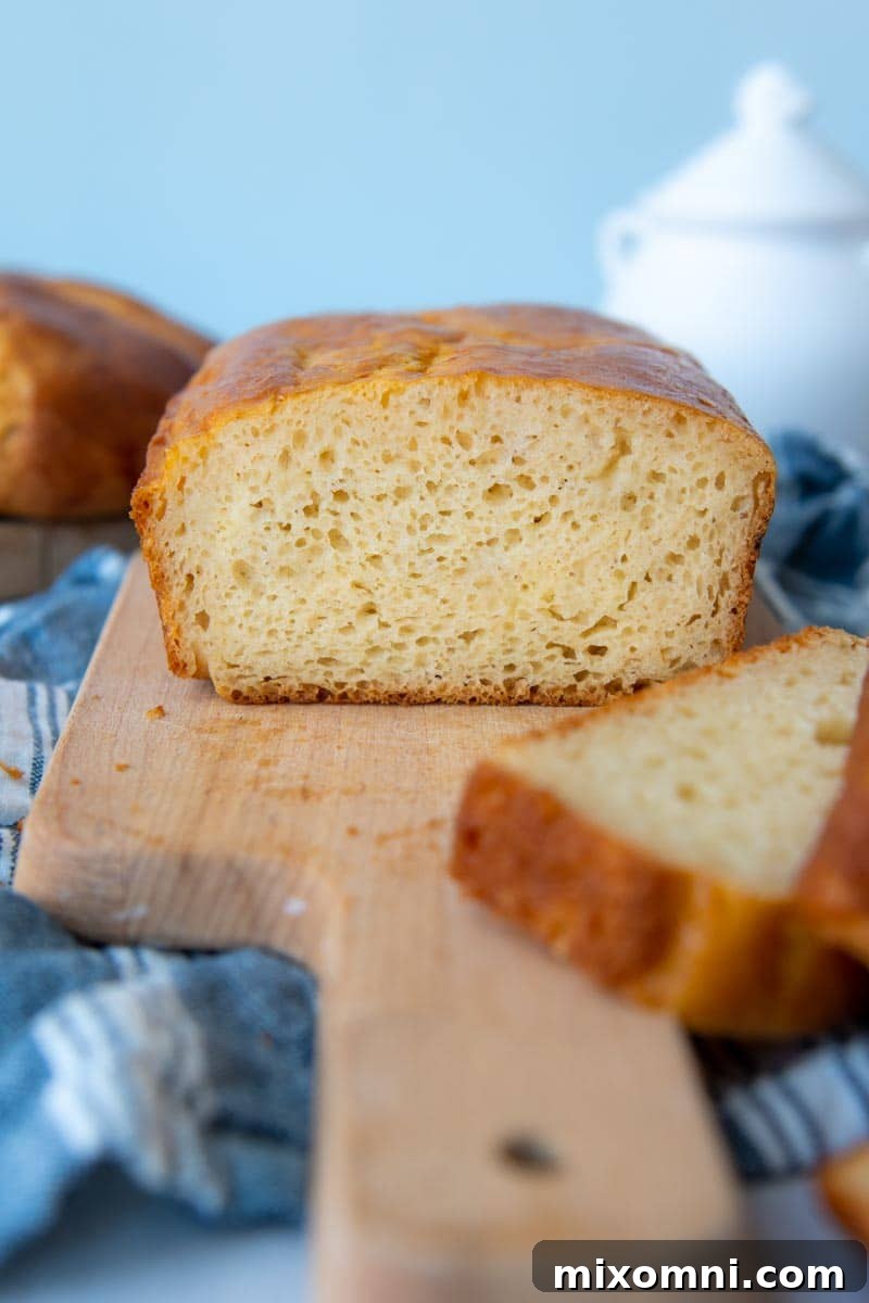 A challah bread loaf sliced open on a wooden cutting board, revealing its soft, fluffy interior.