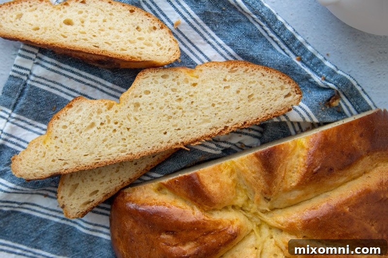 Several slices of golden-brown challah bread arranged on a blue towel, showcasing its inviting texture.