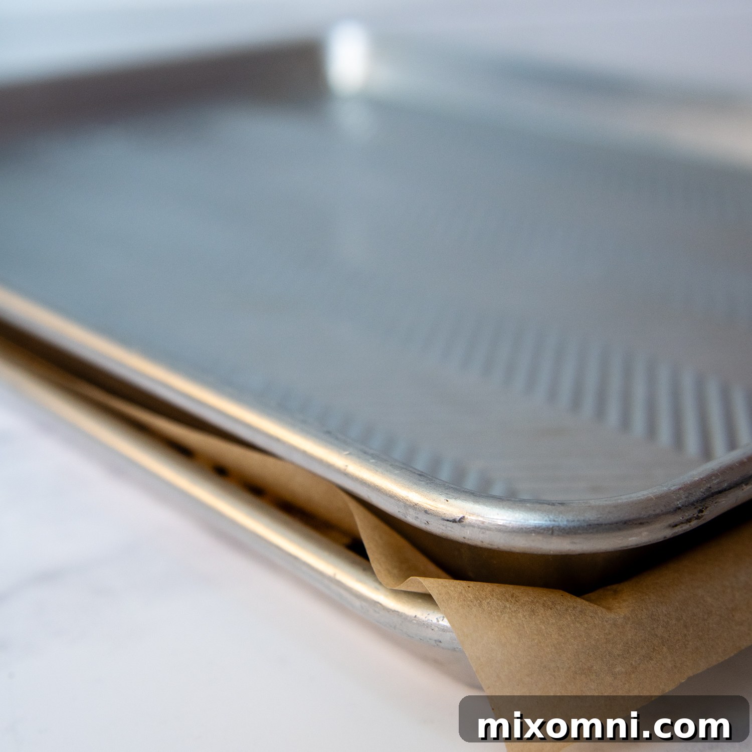 Illustrative image showing how to sandwich the granola mixture between two baking sheets with parchment paper to create perfect clusters.