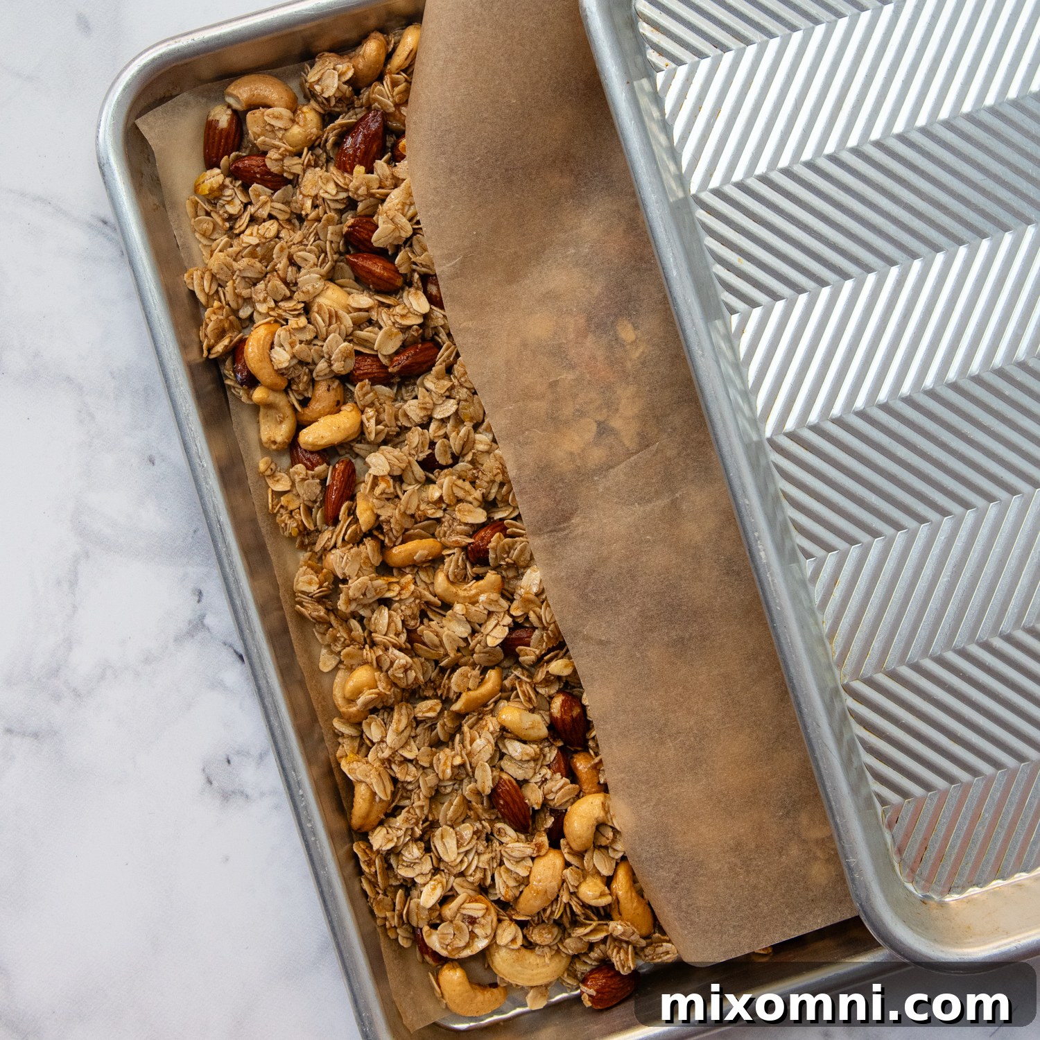 Two sheet pans with baked granola sandwiched between them, demonstrating the unconventional baking technique.