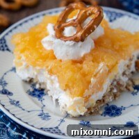 close up of a slice of pretzel salad with pineapple with whipped cream and pretzel on top
