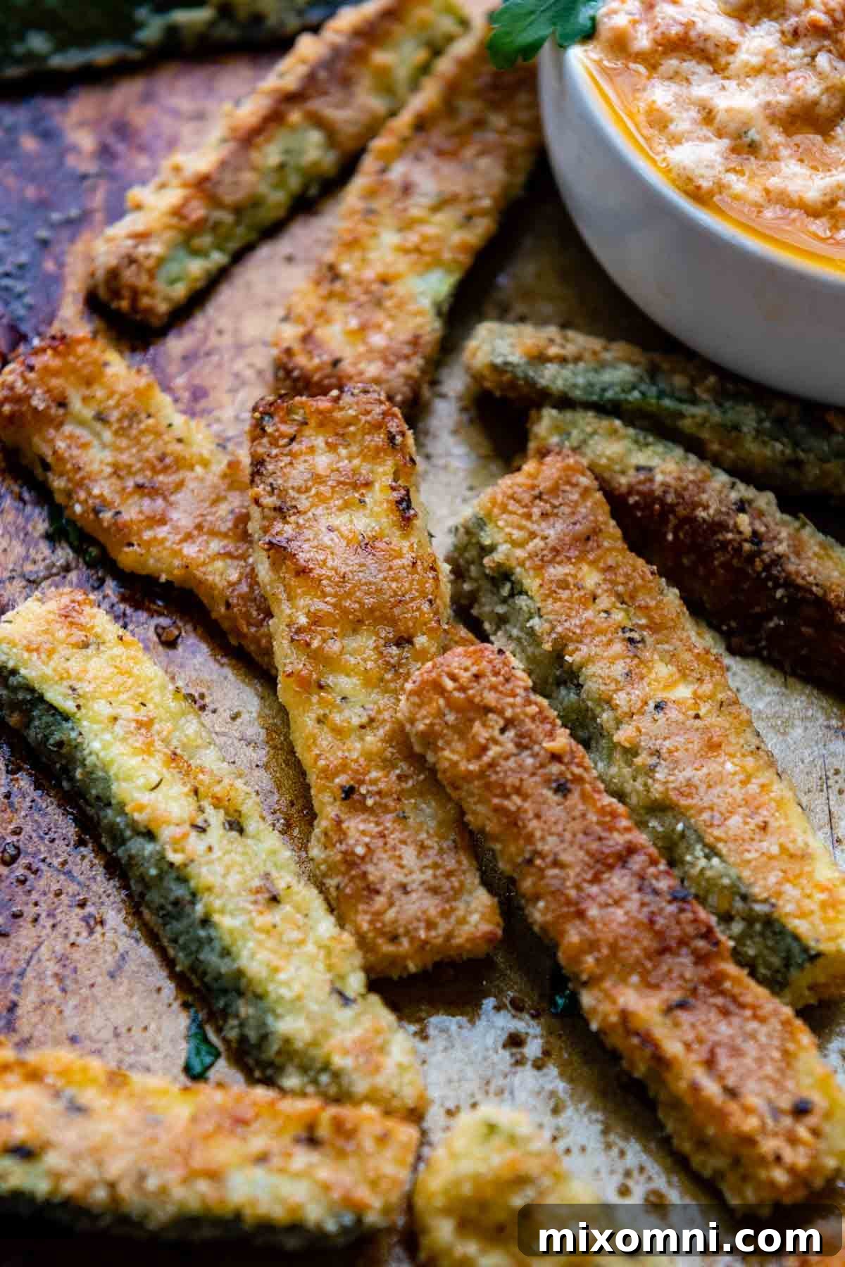 A close-up of golden, crispy gluten-free zucchini fries on a baking sheet, ready to be served.