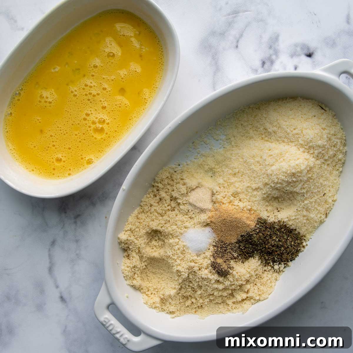 Separate bowls for egg wash and almond flour Parmesan breading, illustrating the dipping station setup.
