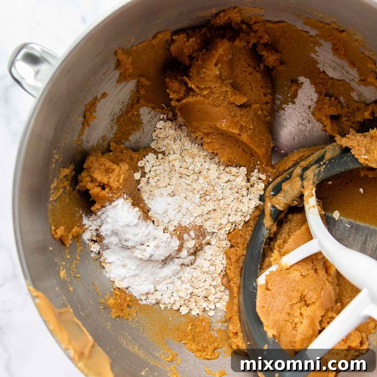 Quick-cooking oats, baking soda, and salt added to the wet ingredients in a large mixing bowl.
