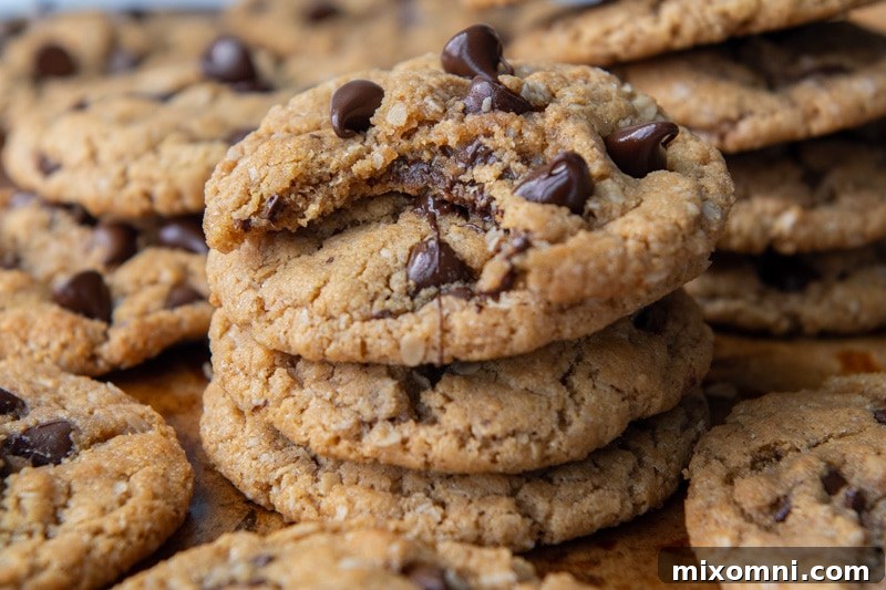 A stack of perfectly baked flourless chocolate chip cookies, with one showing a delightful bite taken out, revealing its soft interior and melted chocolate.