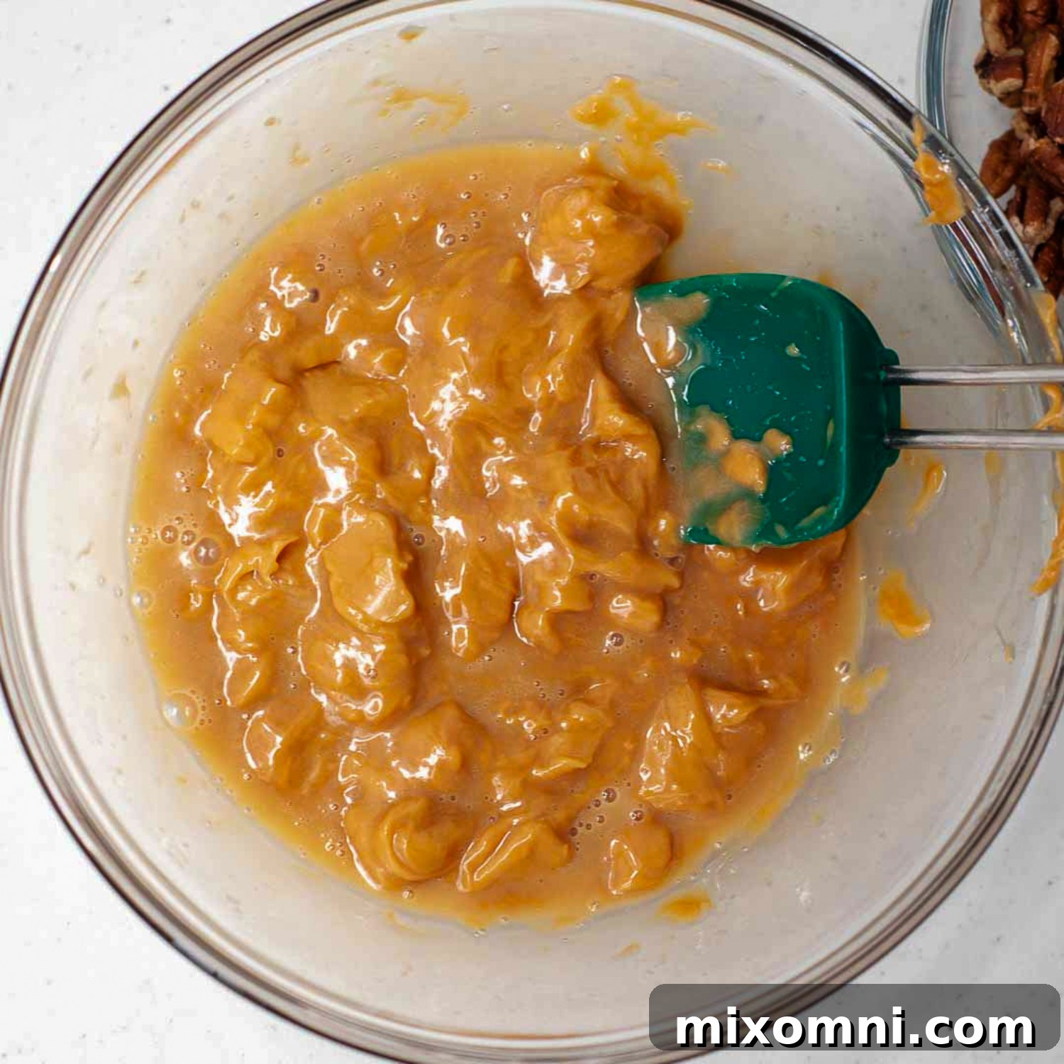 Caramels almost completely melted in a bowl, ready to be stirred into a smooth, gooey mixture for the brownie topping.