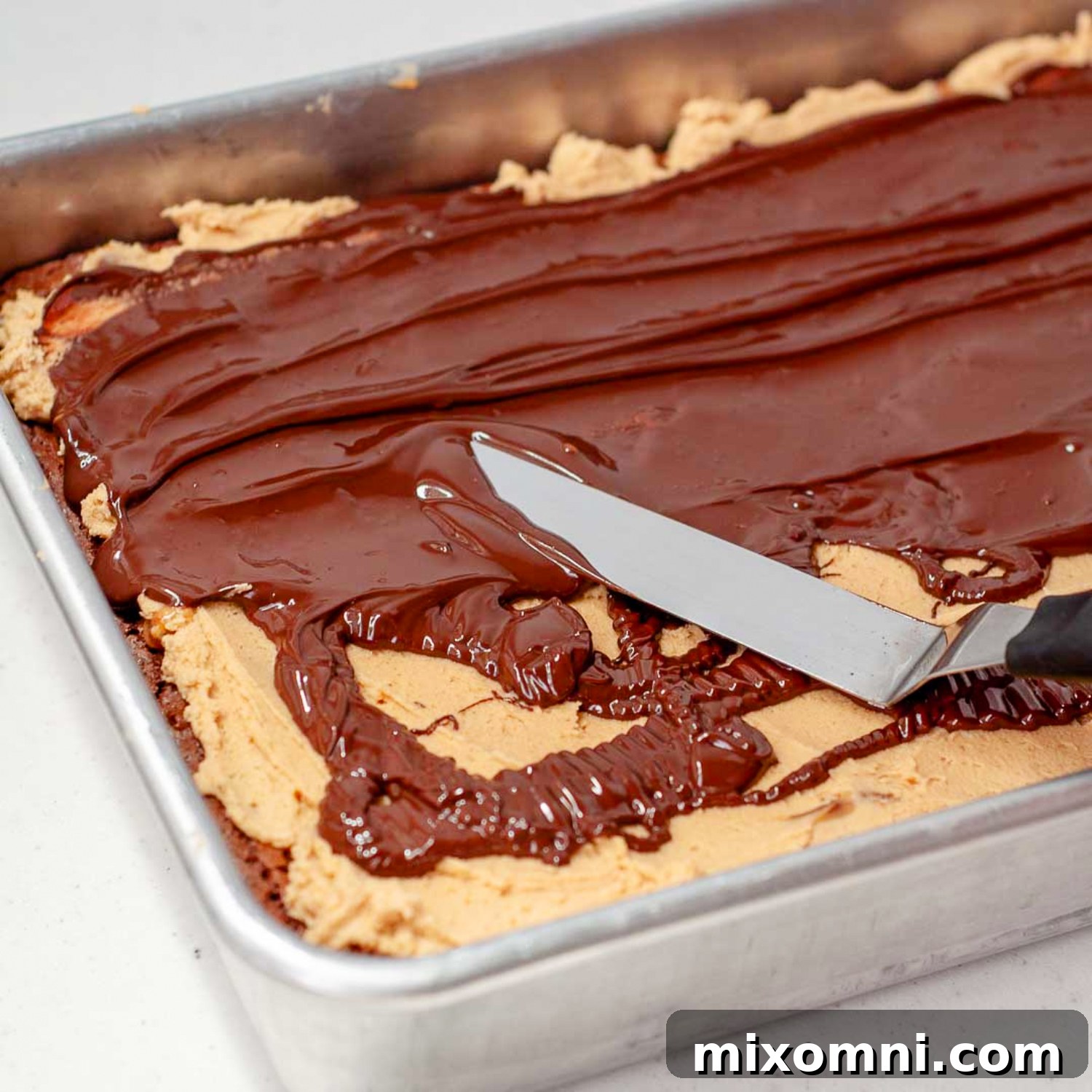 Melted chocolate gracefully spread over a layer of creamy peanut butter, topped with a sprinkle of sea salt, completing the Buckeye Turtle Brownies.