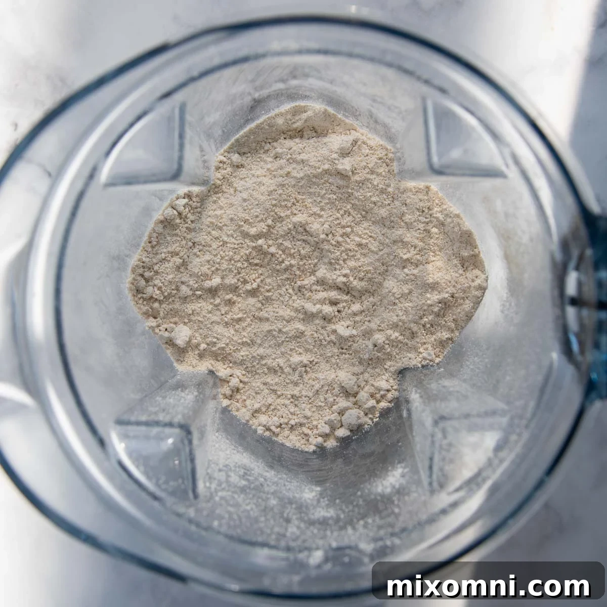 Rolled oats being blended into a fine oat flour in a high-speed blender.