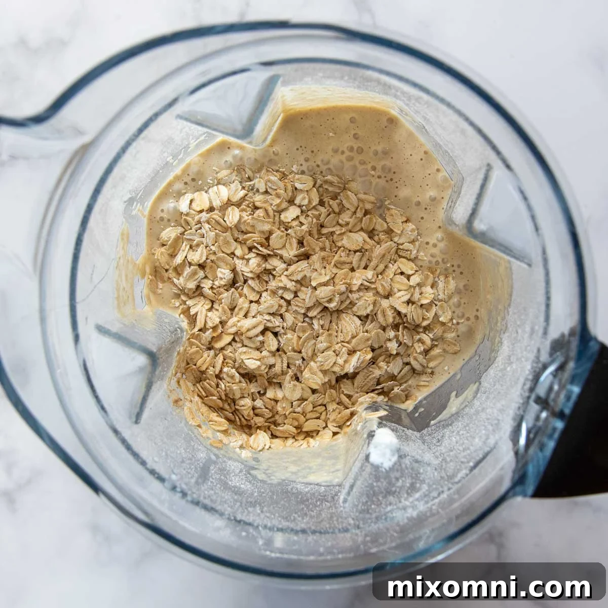 Additional whole oats being pulsed into the oat flour bread batter in a blender.