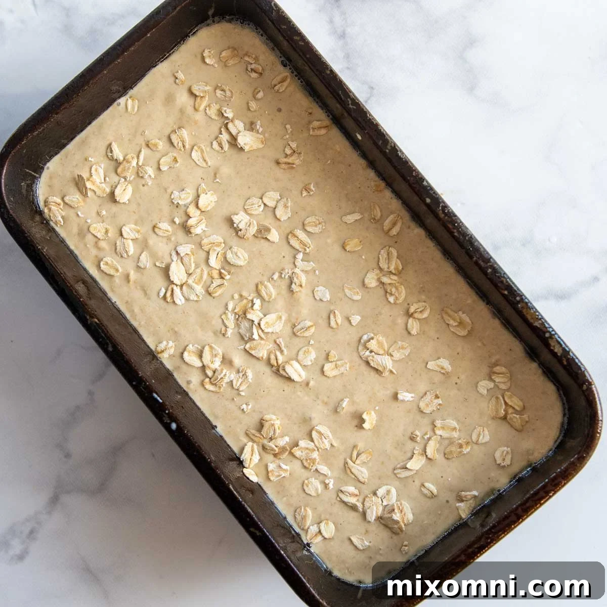 Unbaked oat flour bread batter poured into a greased loaf pan, ready for baking.