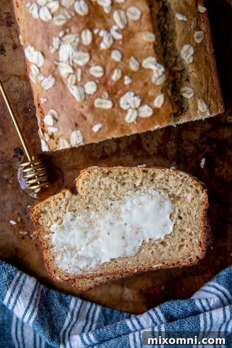 A delectable slice of gluten-free oatmeal bread, face up and spread with butter, ready to be enjoyed.